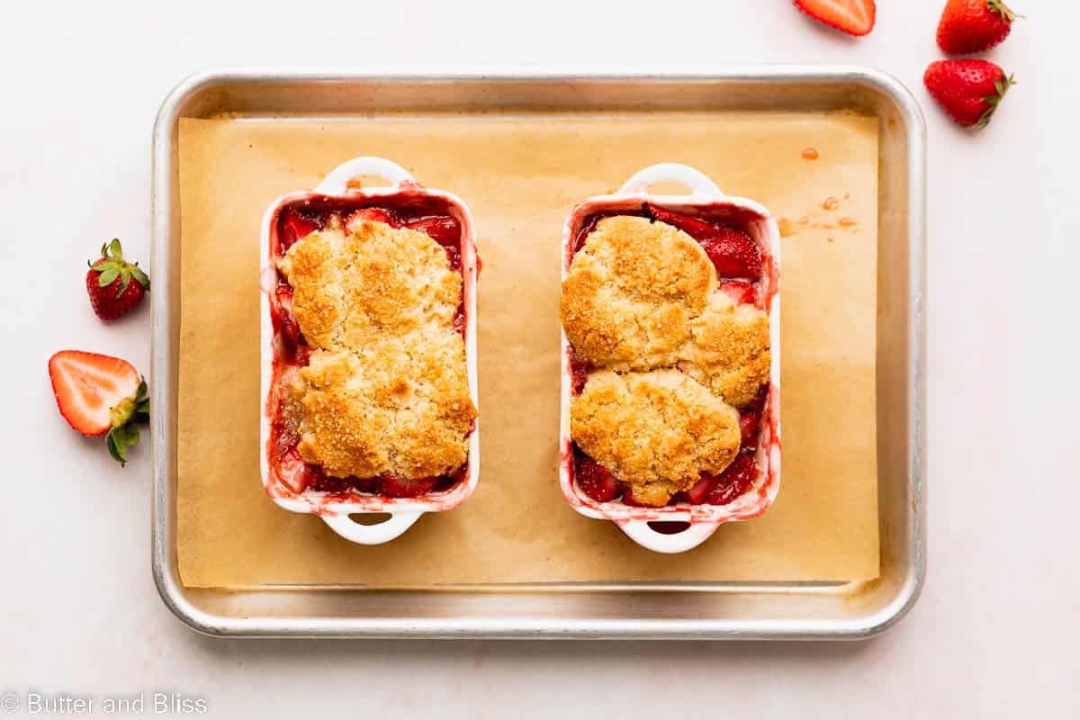 Freshly baked fruit cobbler right from the oven in mini casserole dishes on a baking sheet.