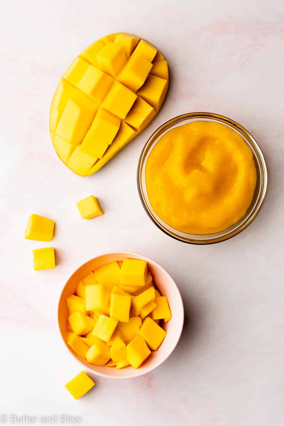 Pretty mango chunks in a bowl next to a bowl of mango puree.