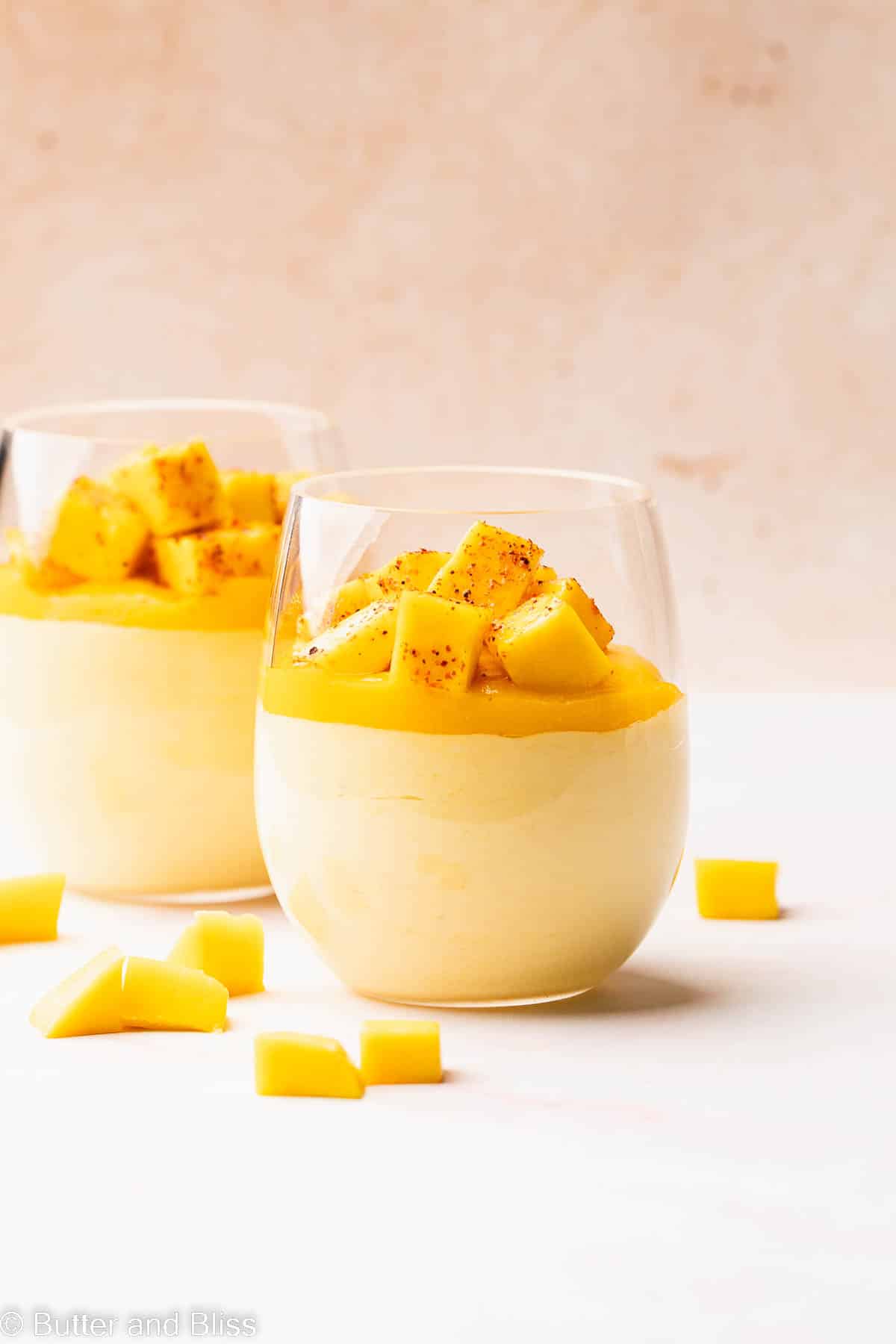 Creamy mango mousse in a parfait glass with a layer of mango puree and mango chunks.