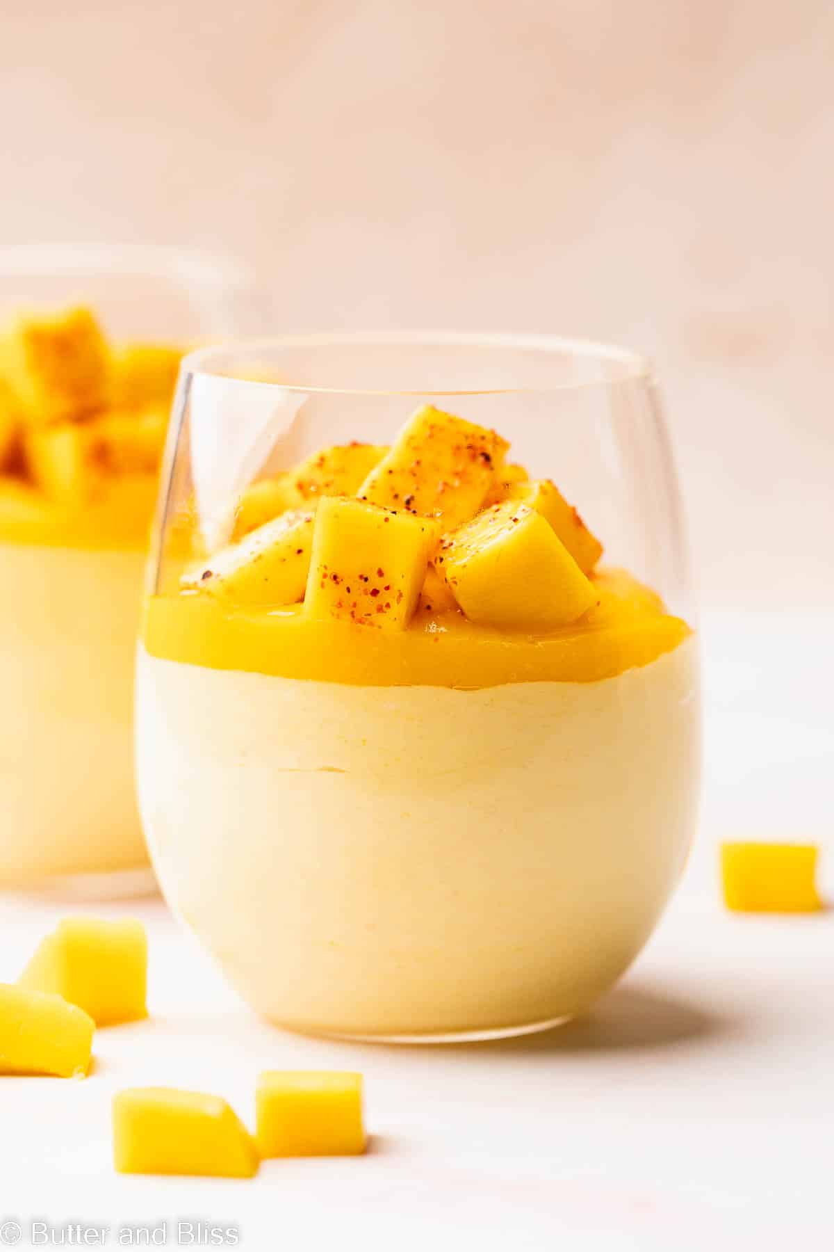 Tropical mango mousse with layers of mango puree and mango chunks in a glass.