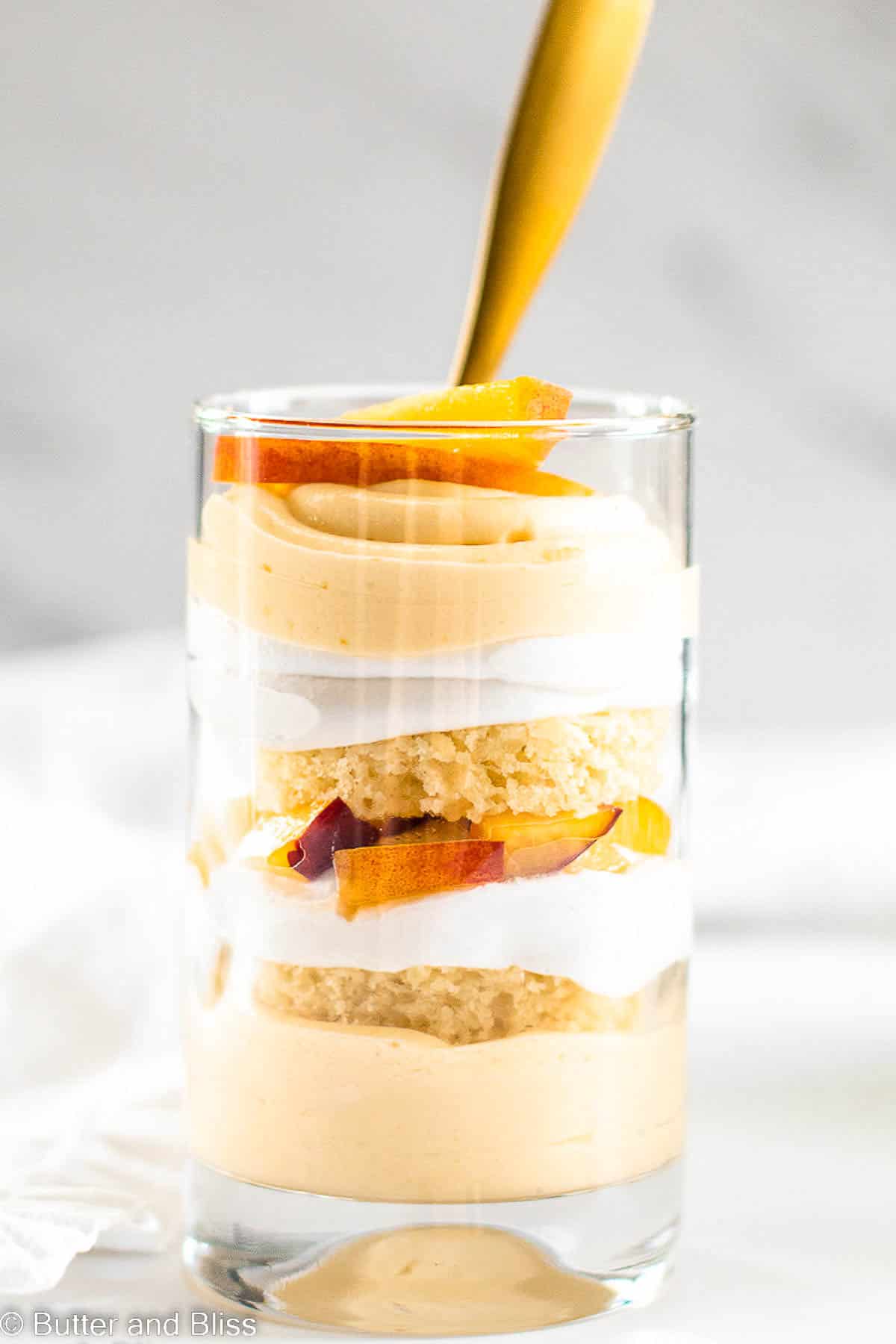 Single serving of peach mousse trifle in a serving glass on a table.