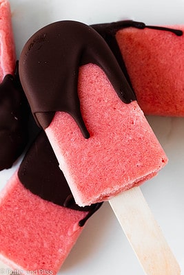 A pile of watermelon popsicles with chocolate shell.