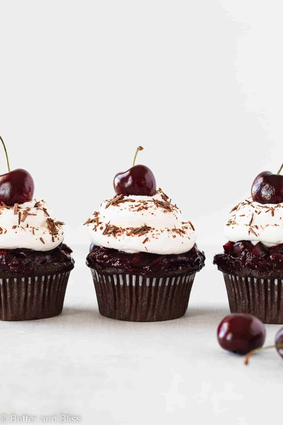 3 sweet chocolate and cherry cupcakes lined up in a row.