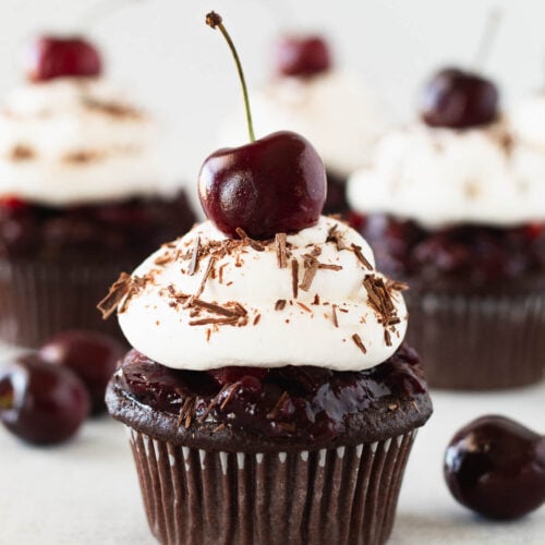 Beautiful black forest cupcake topped with whipped cream and a fresh cherry.