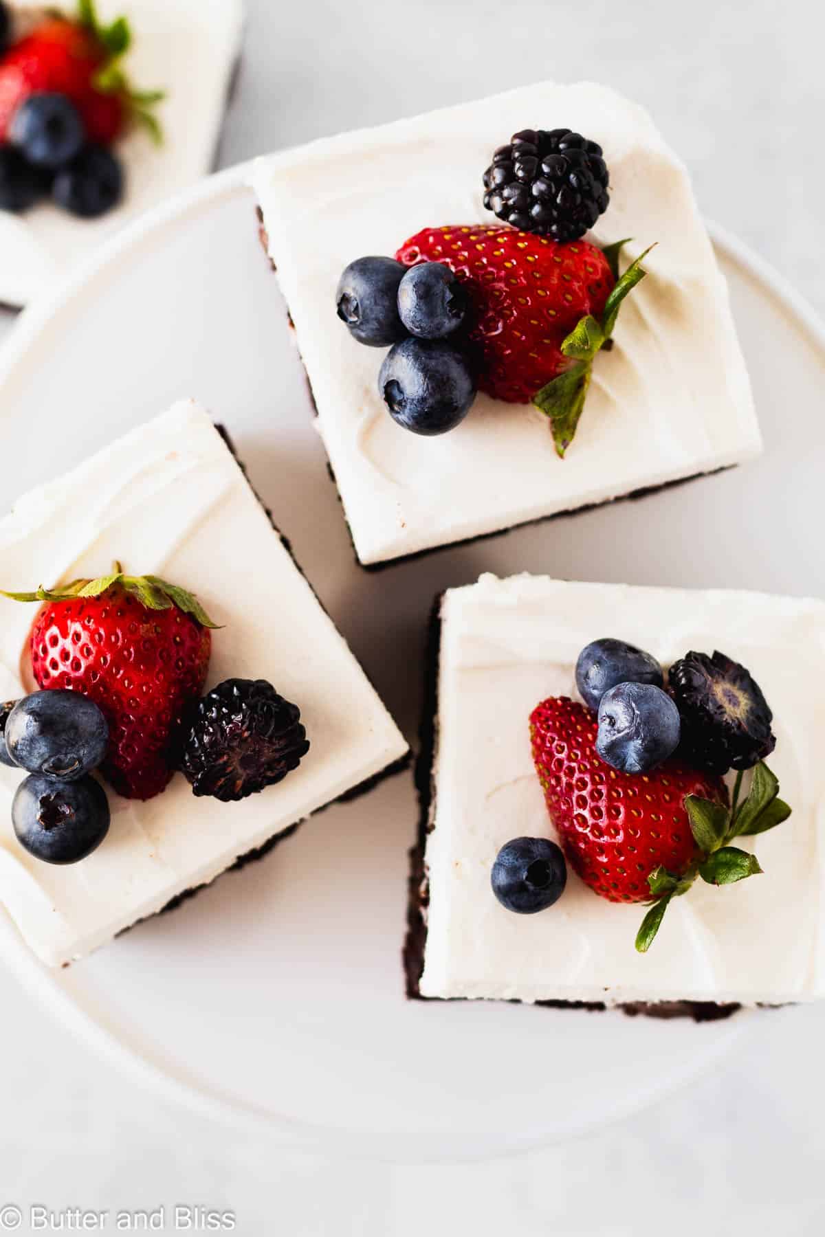 A tray of brownies with whipped topping with fresh fruit garnish.