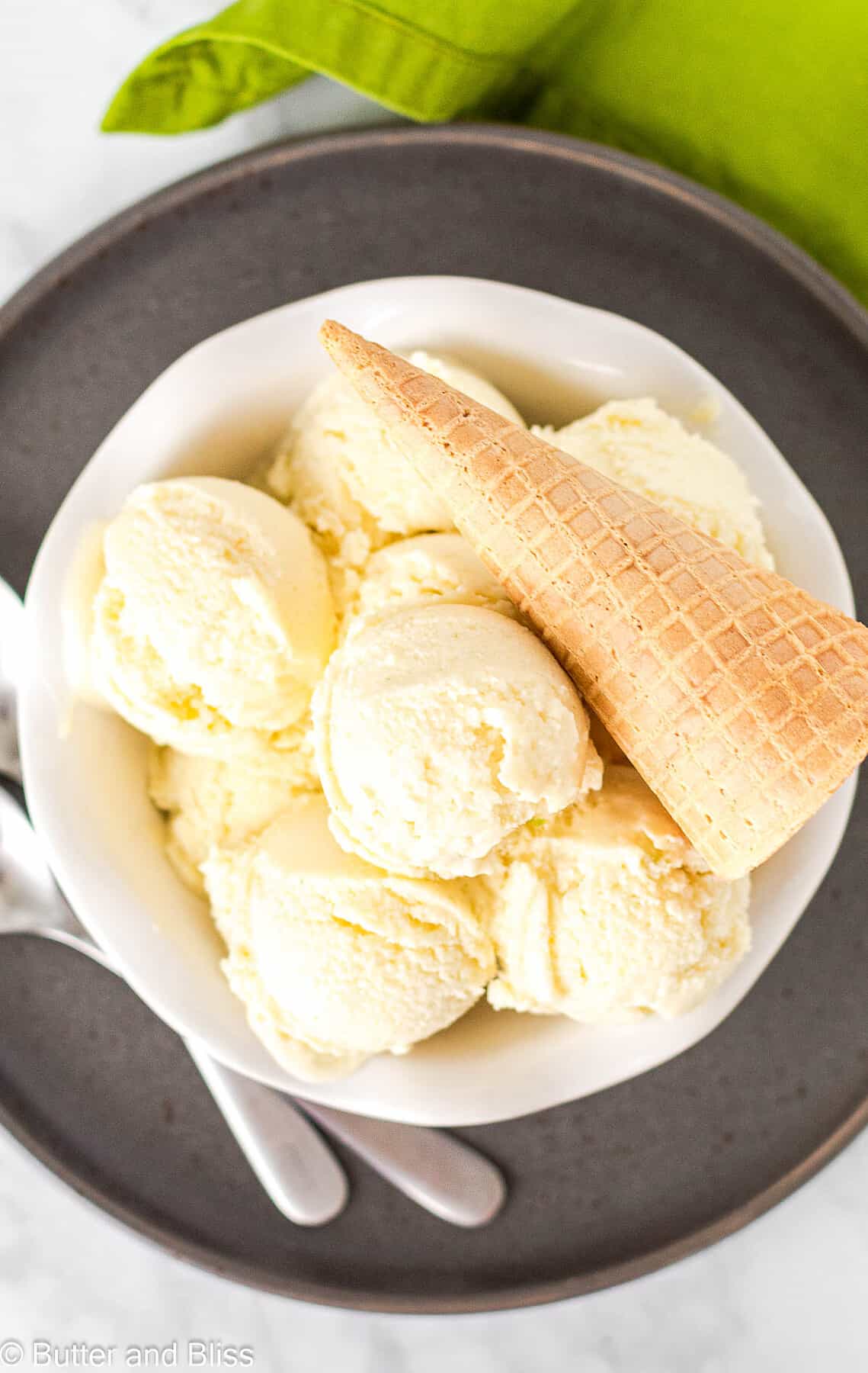 A white bowl full of pina colada ice cream scoops with a sugar cone decoration.