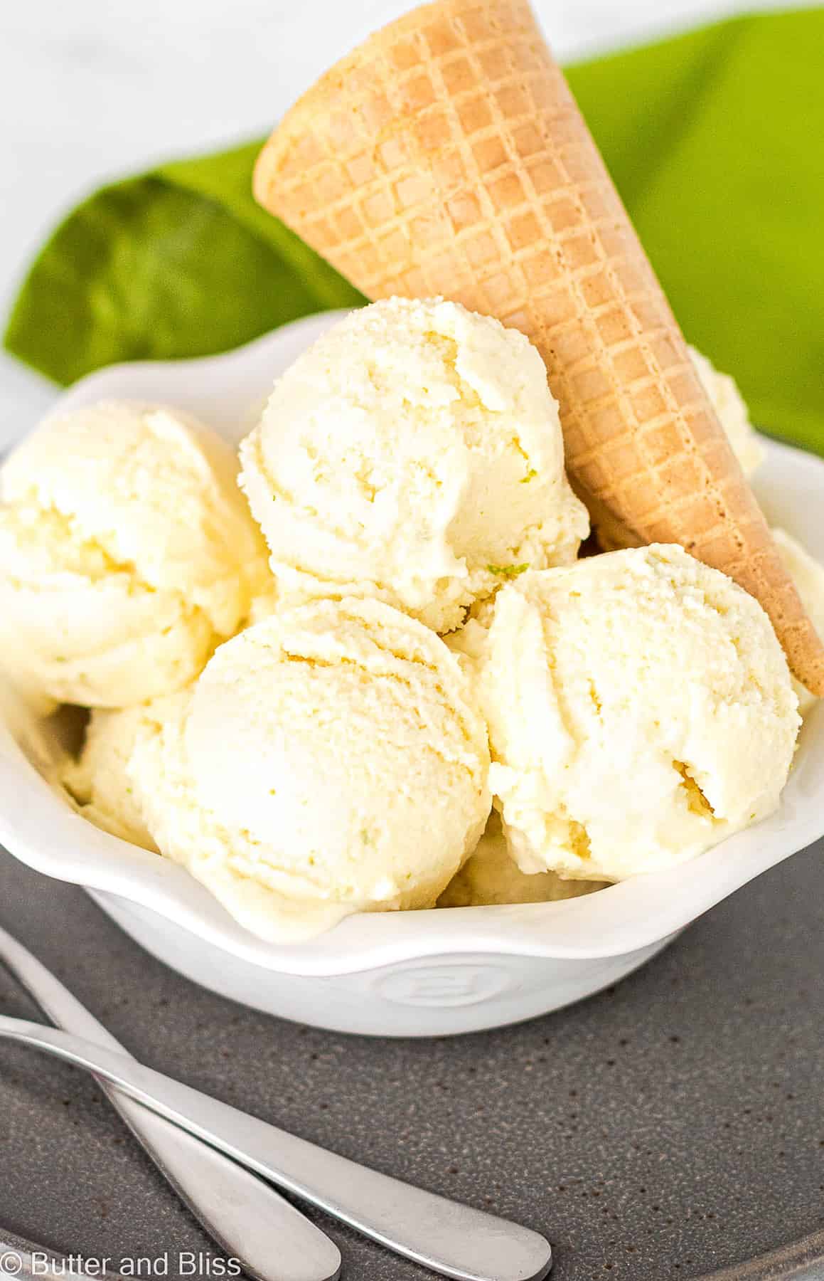 Pretty white bowl of scoops of pina colada dairy free ice cream with a sugar cone garnish.