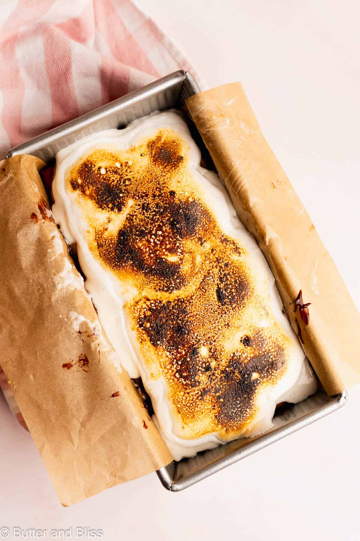 Toasty marshmallow topping on a gluten free s'mores icebox cake in a loaf pan.