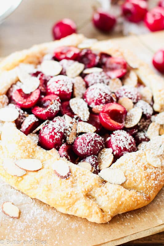 The best cherry almond galette for two on a piece of parchment paper and dusted with powdered sugar.