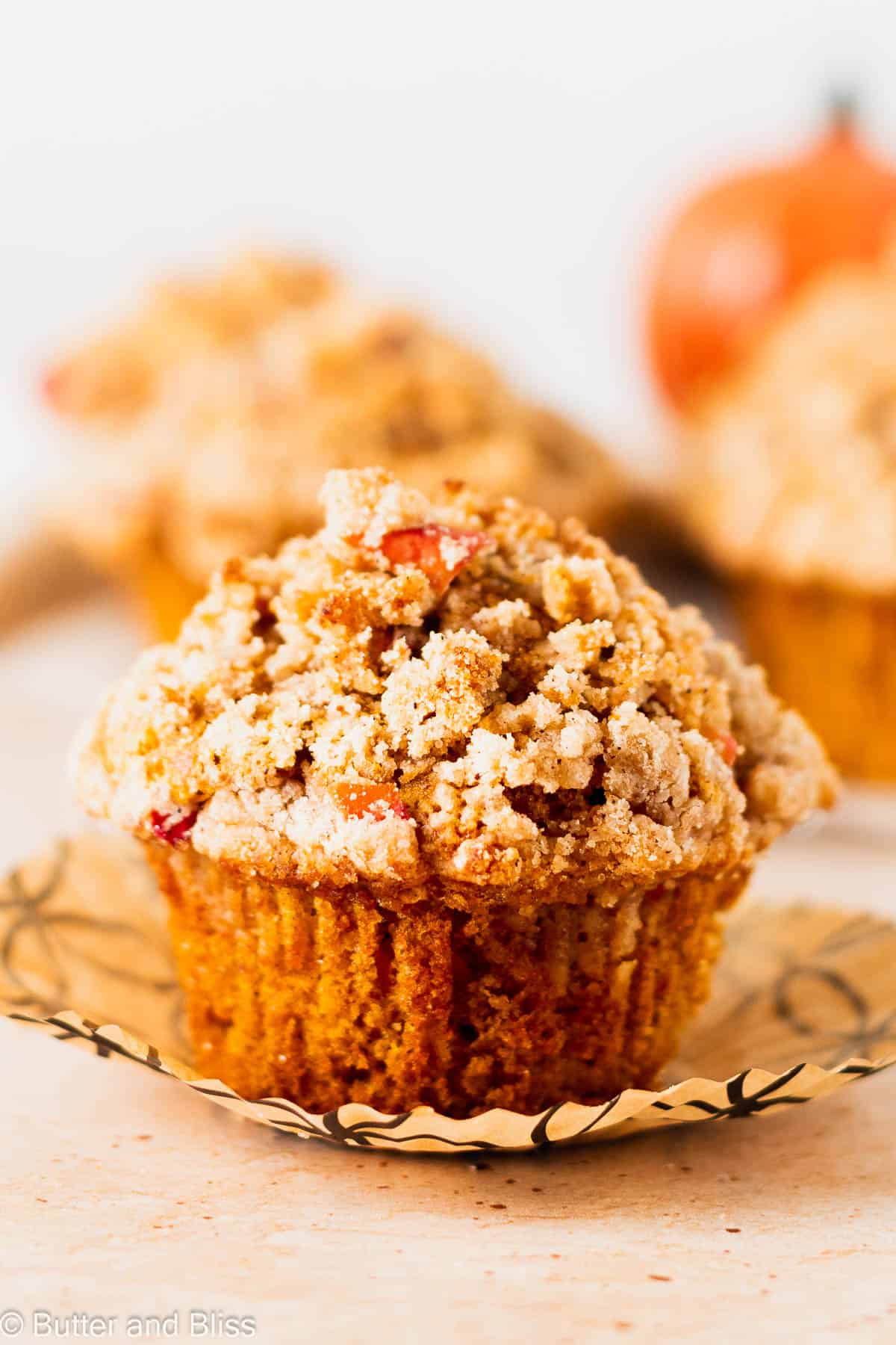 Warm and cozy pumpkin apple muffin with streusel topping on a table.