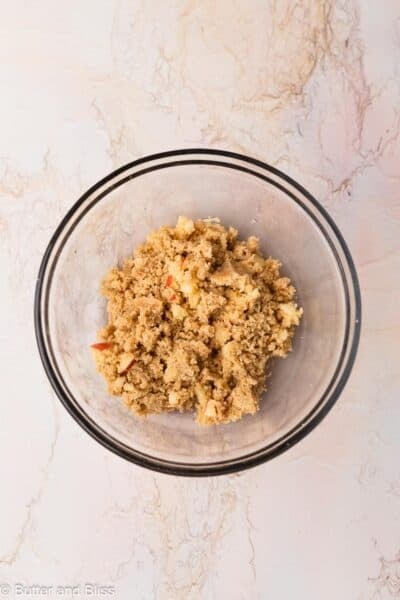 Streusel studded with small apple pieces in a mixing bowl.