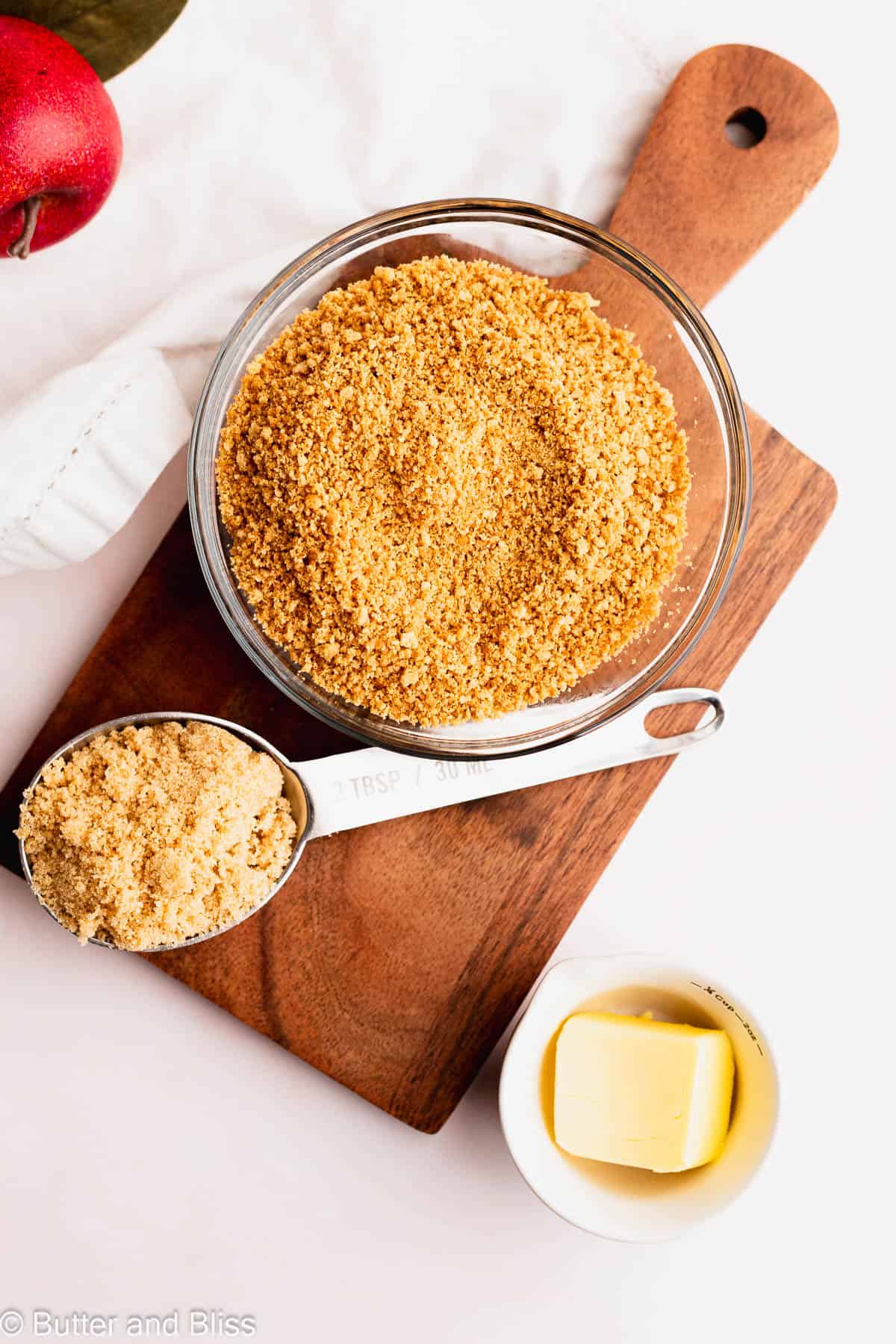 Graham cracker crumbs in a small bowl set on a wood trivet.
