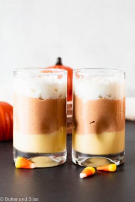 Two candy corn pudding parfaits lined up in a pretty parfait glasses.