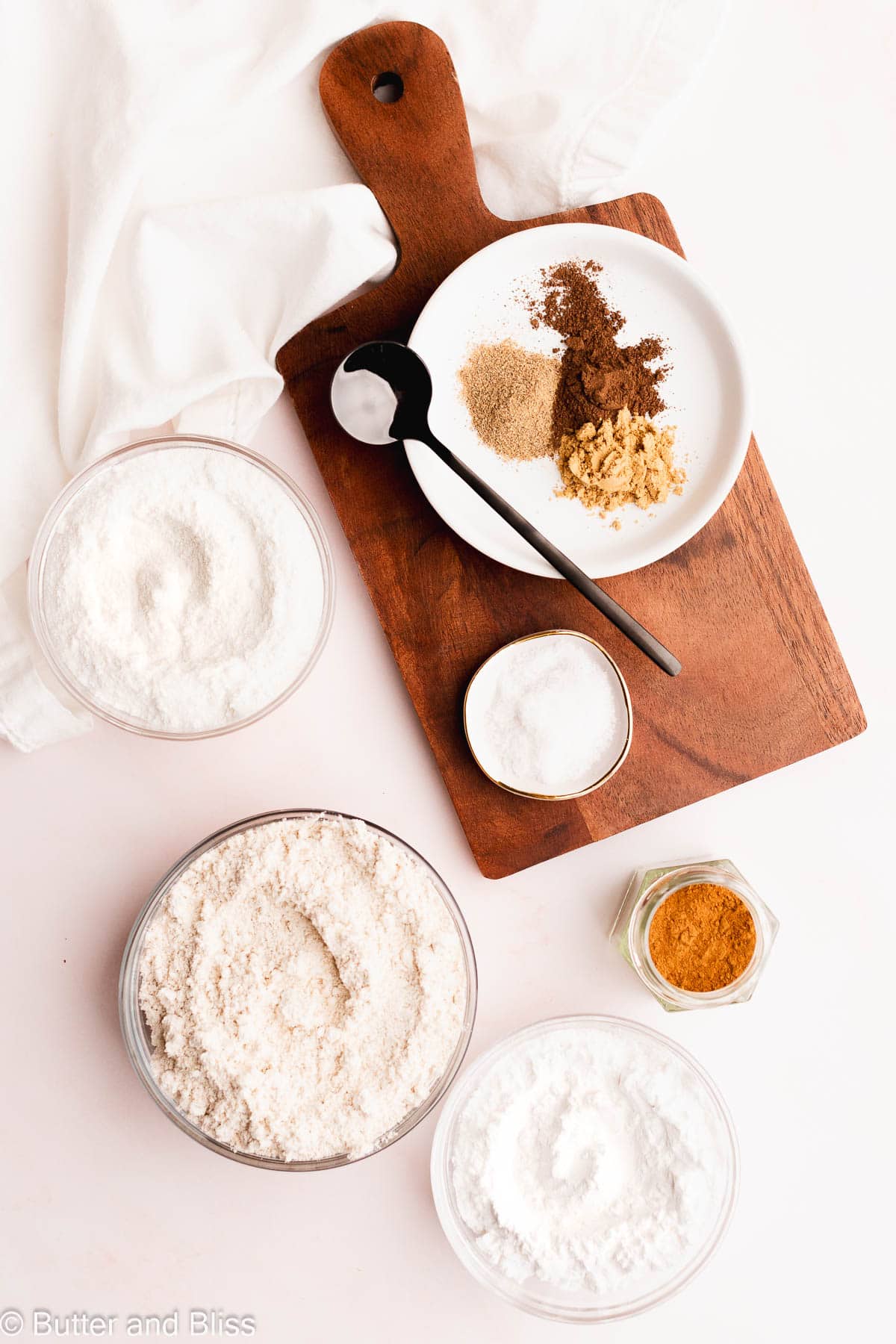 Dry ingredients in small glass bowls for fall flavored bread arranged on a table.