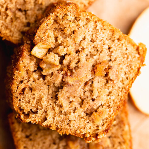 Slices of apple spice gluten free bread stacked on top of each other bursting with apples.