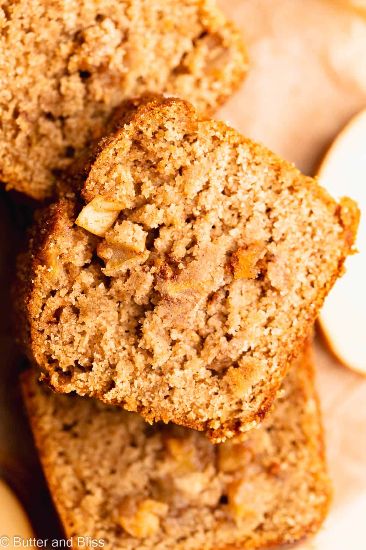 Slices of apple spice gluten free bread stacked on top of each other bursting with apples.