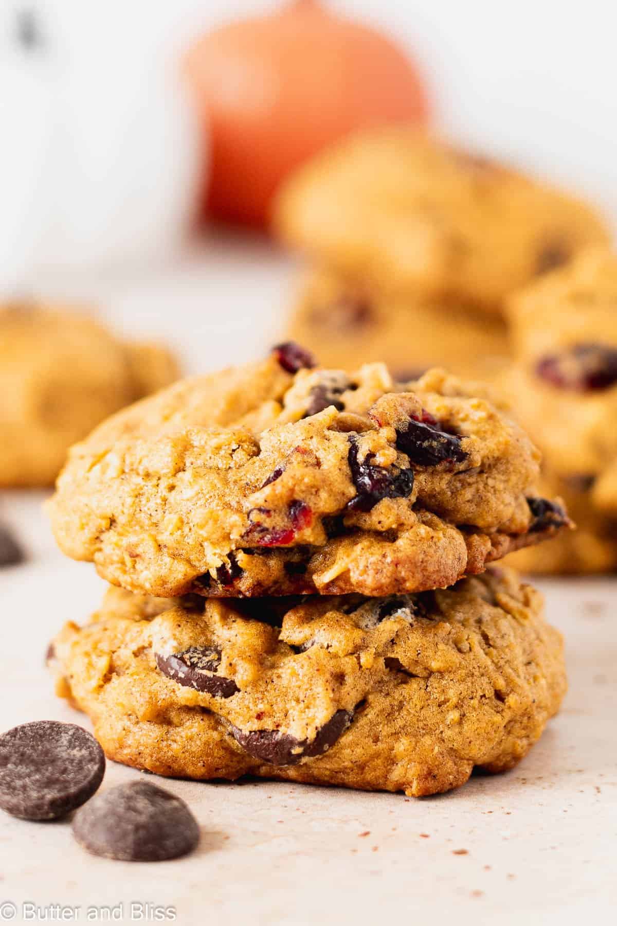 Two fluffy pumpkin oatmeal cookies with chocolate chips on a table.