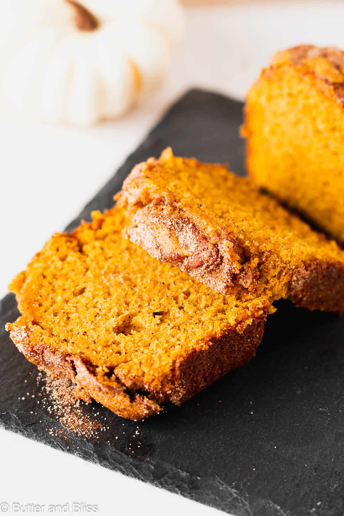 Slices of moist pumpkin bread with cinnamon topping on a small black plate.