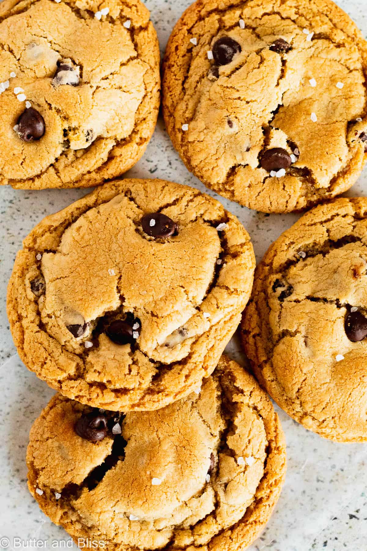 Caramel stuffed chocolate chip cookies in a pile on a table.
