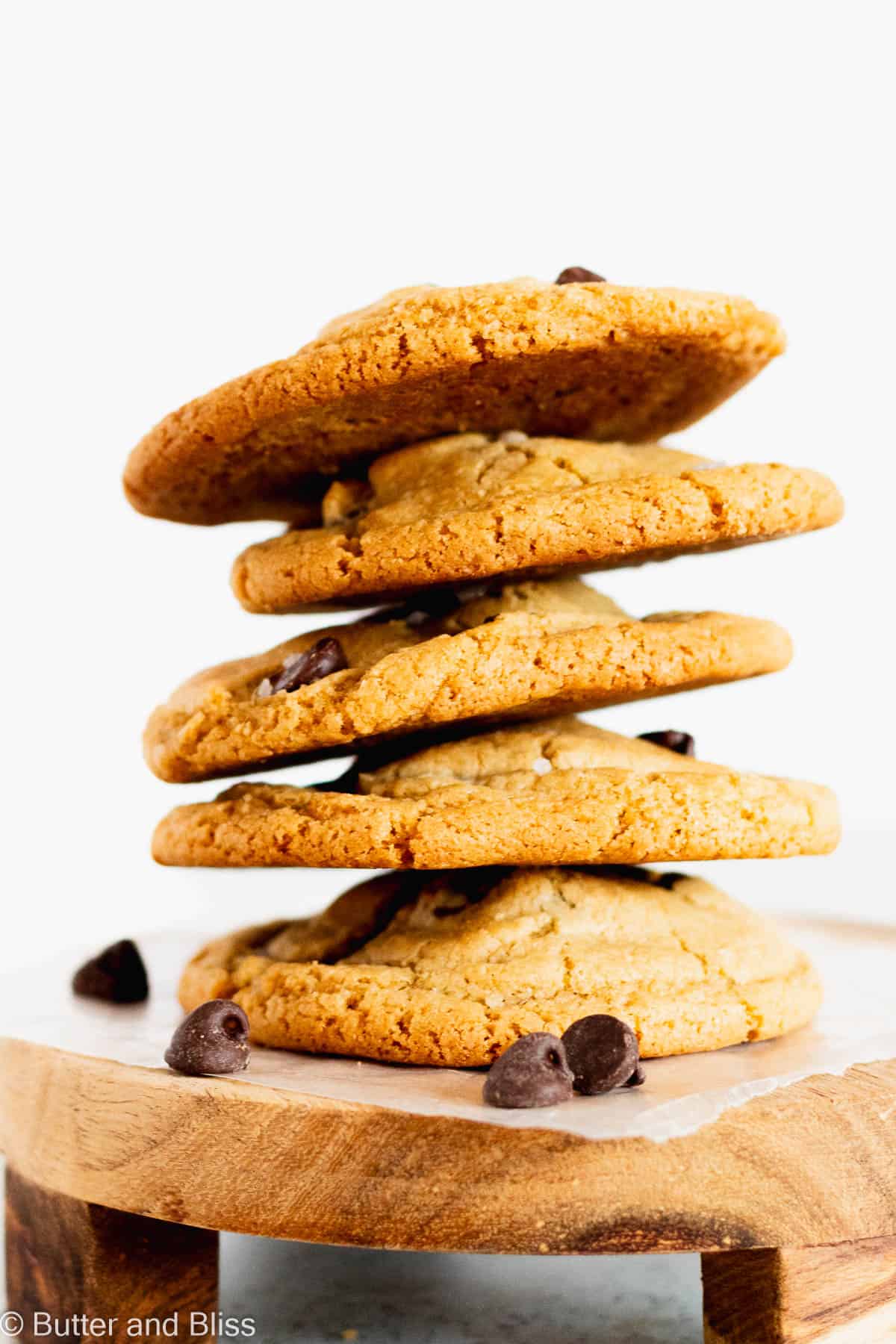 A stack of bakery-style cookies on a small wood platter.