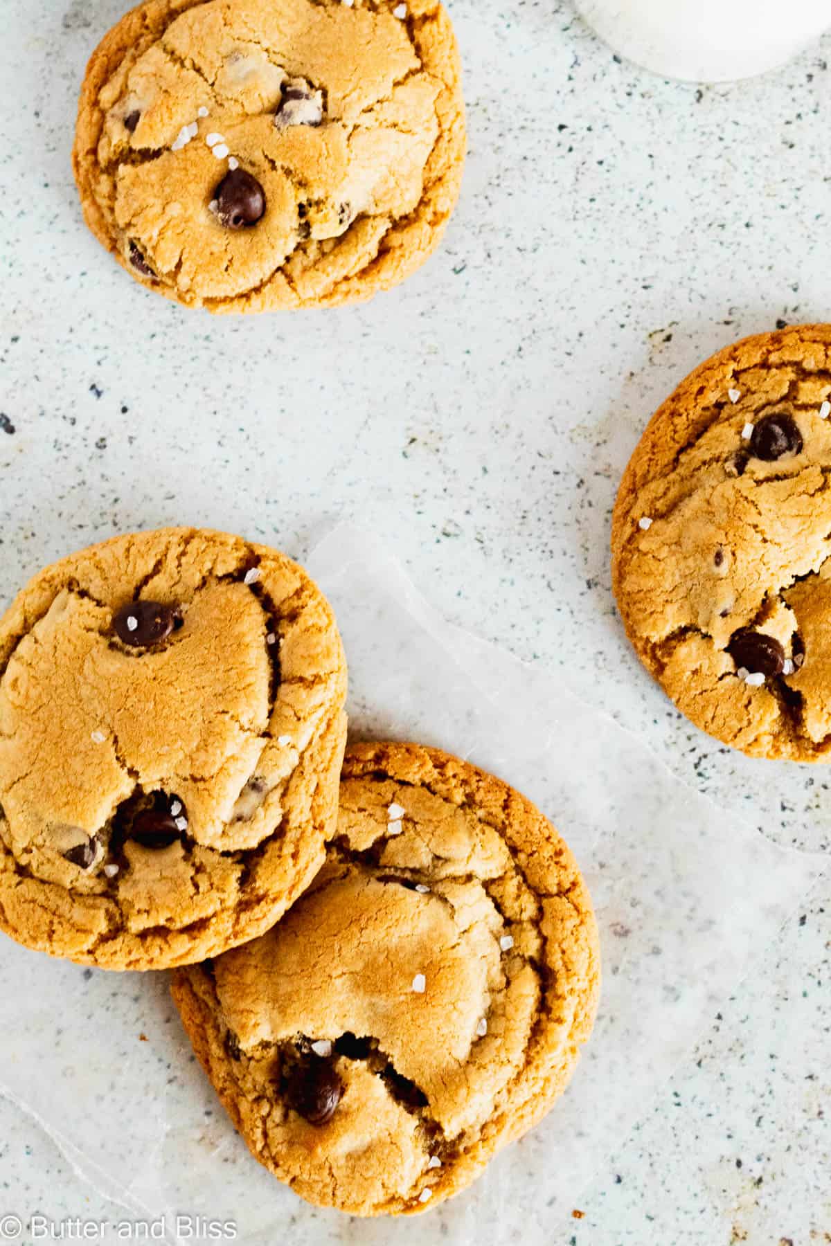 Caramel chocolate chip cookies on a table with a glass of milk.