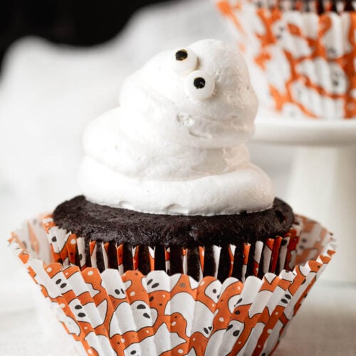 Googly eyed marshmallow ghost Halloween cupcakes in cut Halloween cupcake liners.