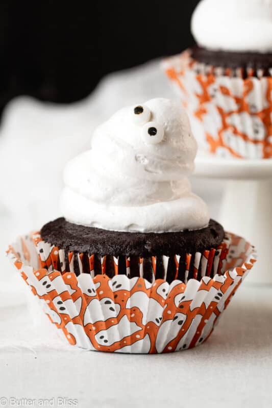 Googly eyed marshmallow ghost Halloween cupcakes in cut Halloween cupcake liners.