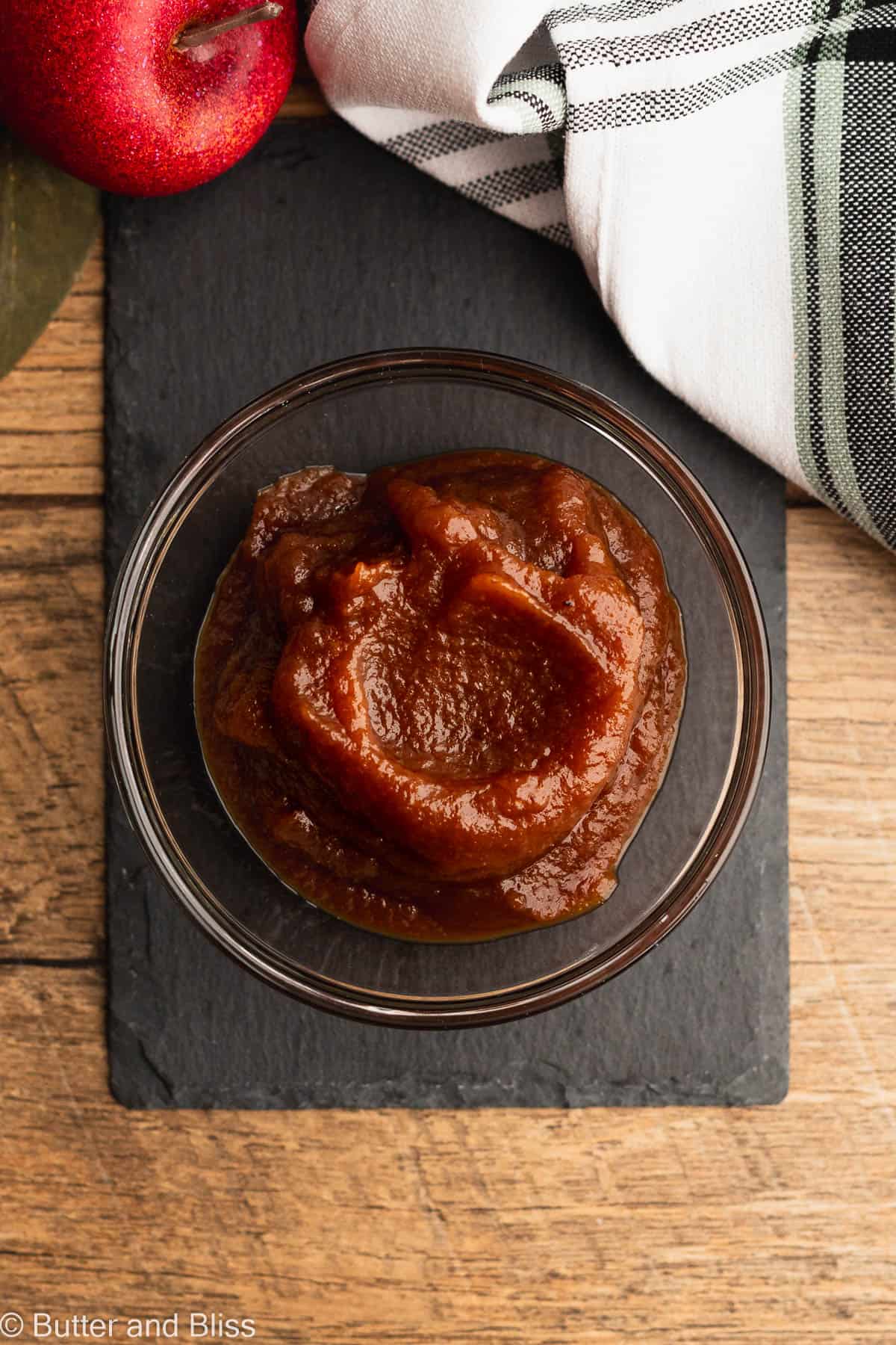 A bowl of creamy apple butter on a black plate.