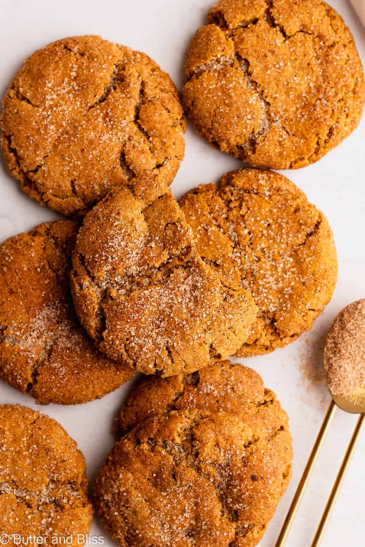 Freshly baked fall spice cookies arranged in a pile on a table with cinnamon sugar.