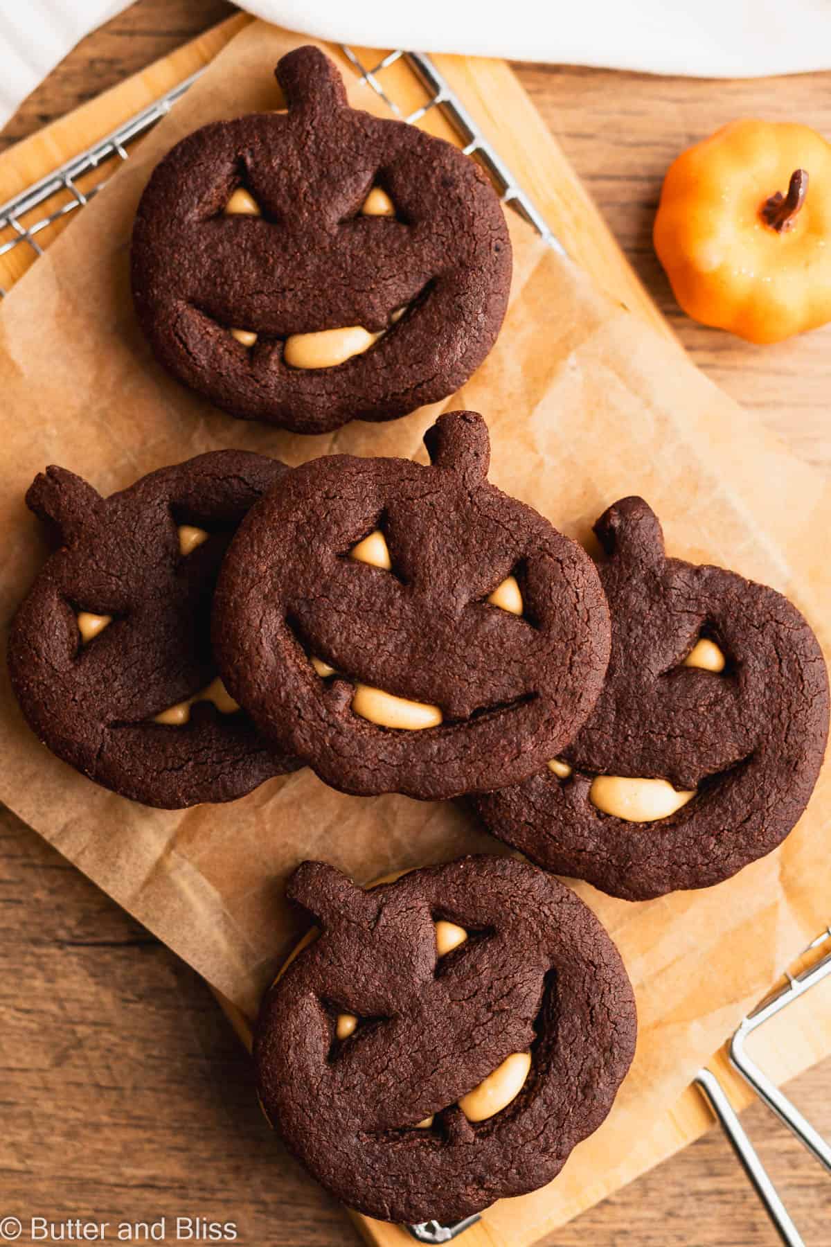 Chocolate Halloween peanut butter cookie sandwiches arranged on a piece of parchment paper.
