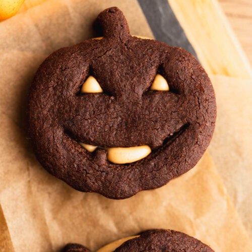 A cute Halloween cut-out chocolate cookie filled with peanut butter on a piece of parchment paper.