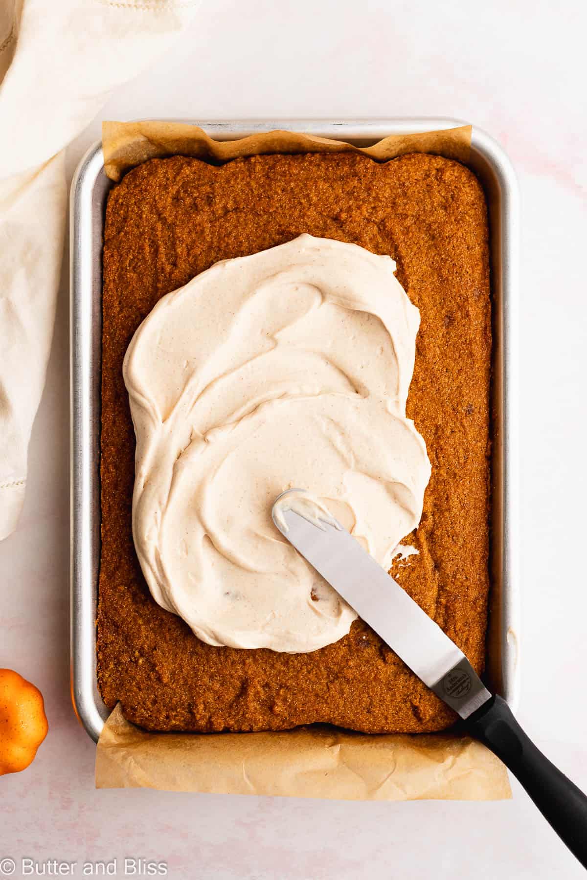 Fresh baked fall dessert in a baking pan covered in cream cheese frosting.