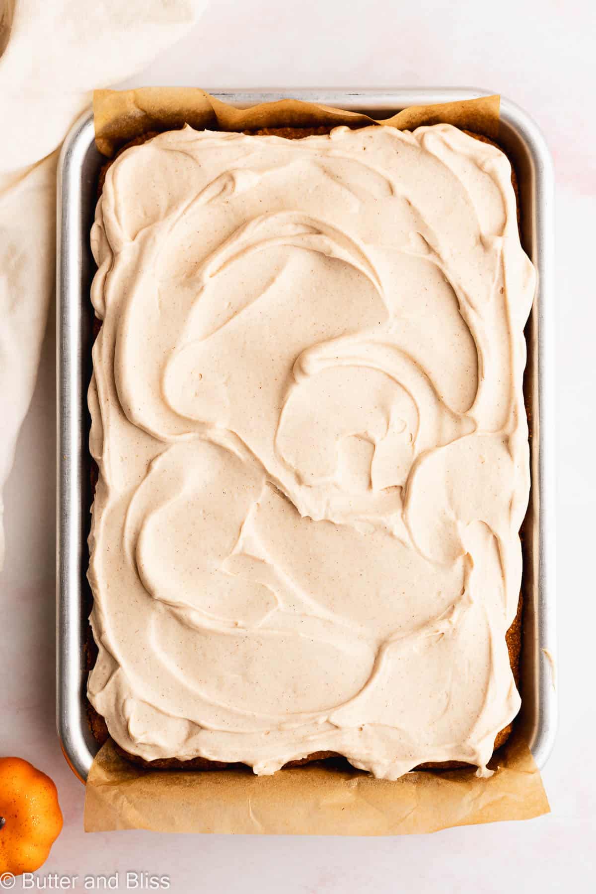 Cream cheese frosting on top of freshly baked fall treats in a baking pan.