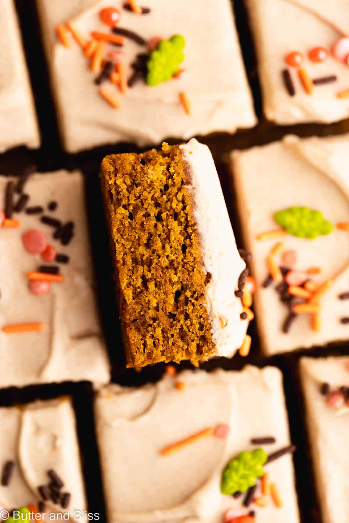 Close up of a slice of moist pumpkin bar with cream cheese frosting.