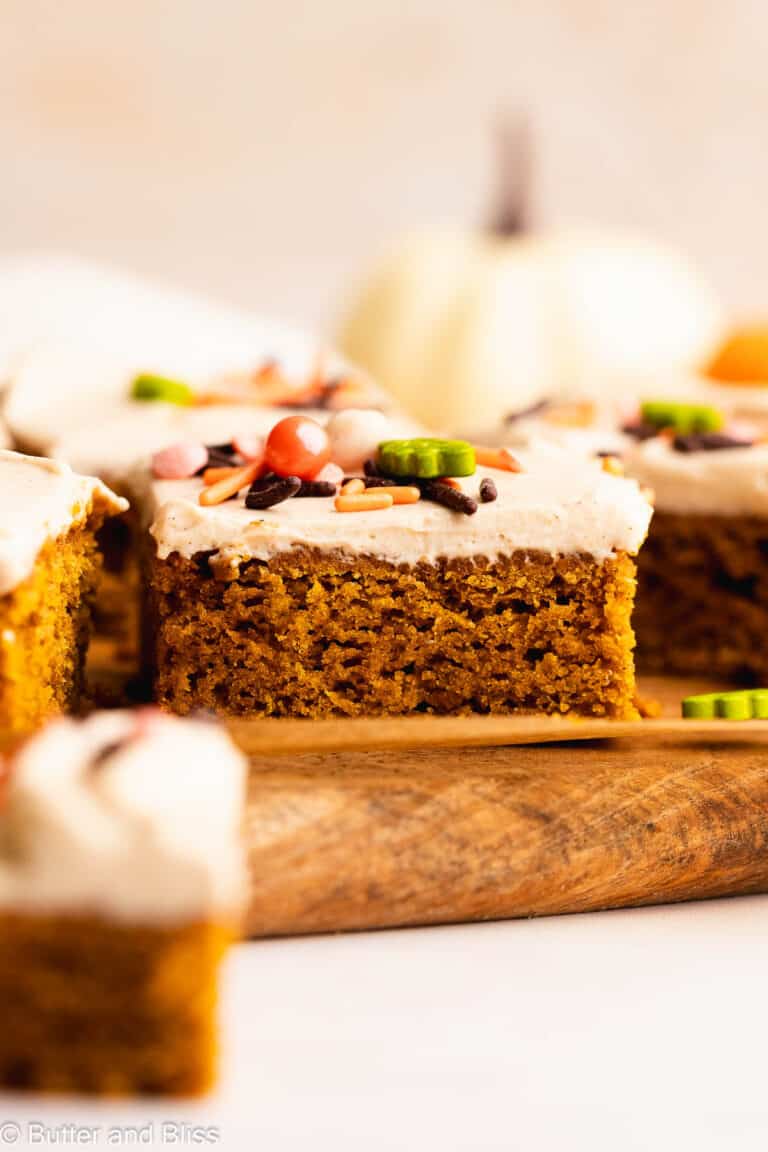 Single slice of super moist gluten free pumpkin bar on a wood table and covered in sprinkles.