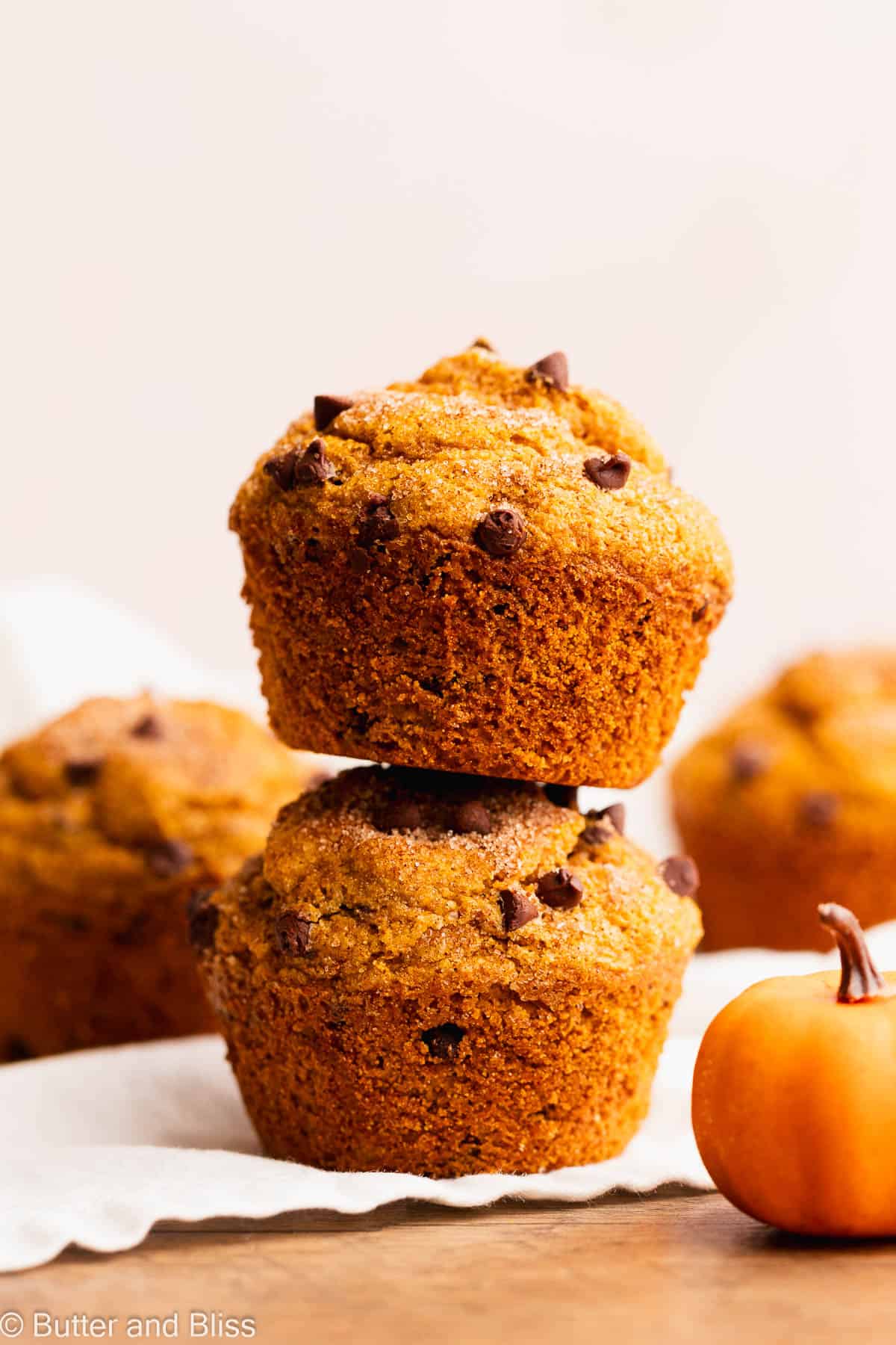 Two tall and moist gluten free pumpkin chocolate chip muffins stacked on top of eachother.
