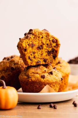 Bite shot of a gluten free pumpkin muffin with chocolate chips stacked on another muffin.