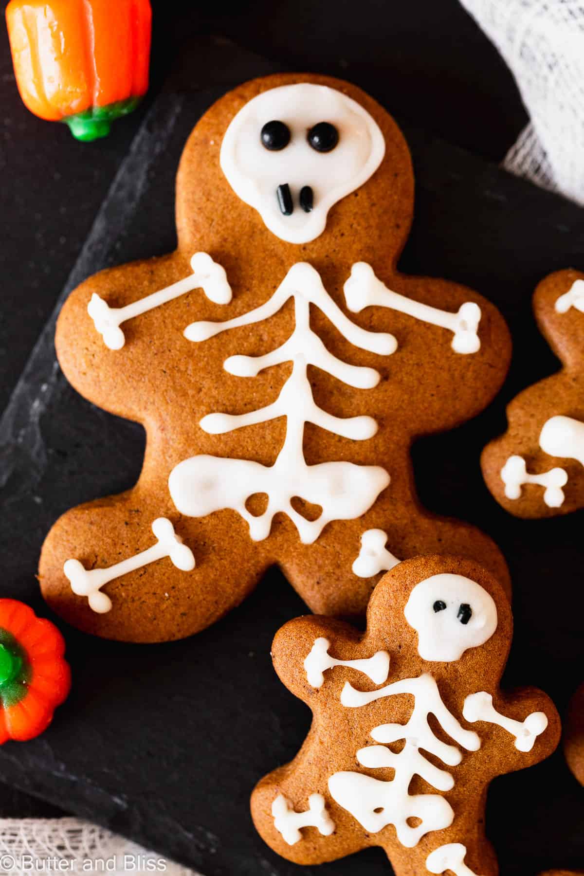 Gingerbread cut-out cookies decorated like skeletons on a small black plate.
