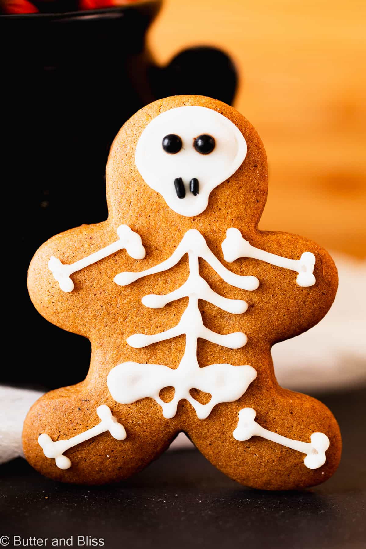 Super cute gingerbread skeleton cut-out cookie propped up on a table.