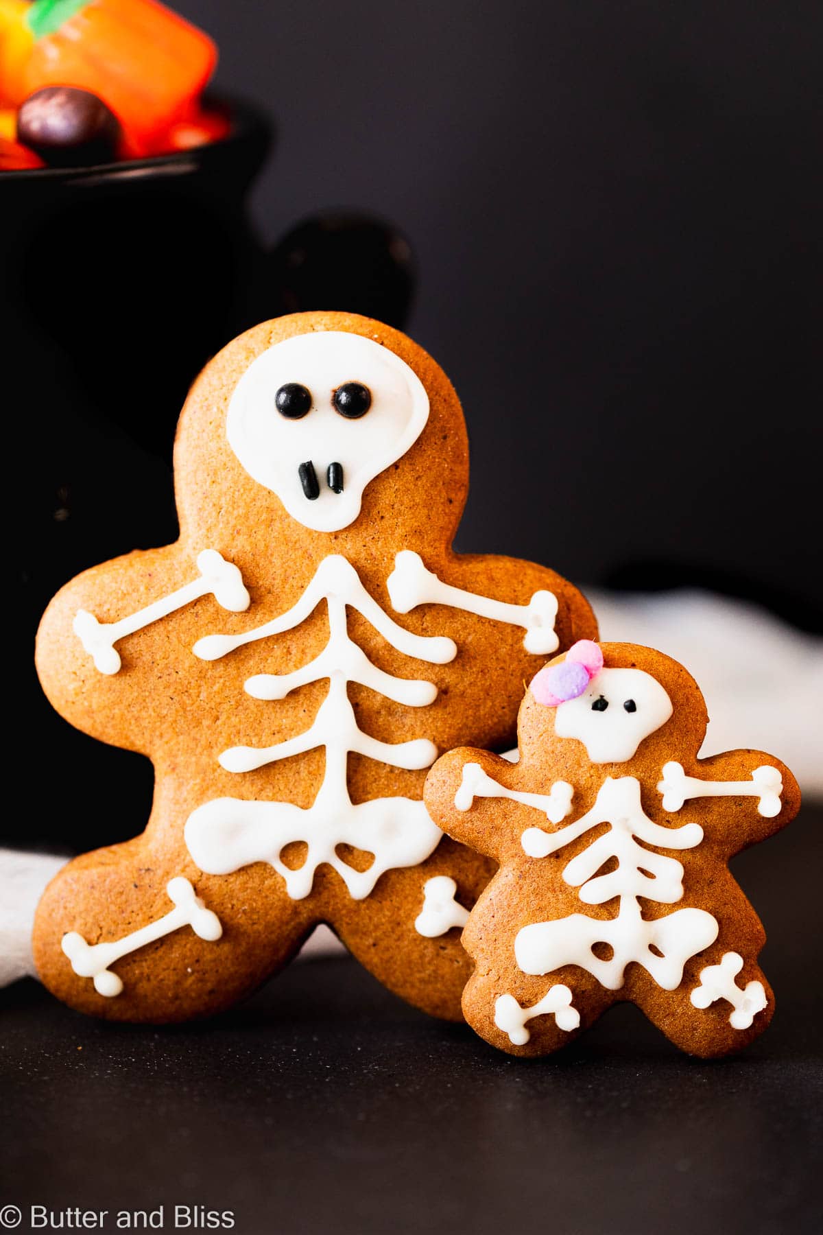 Momma and baby gingerbread skeleton cookies on a spooky black table.