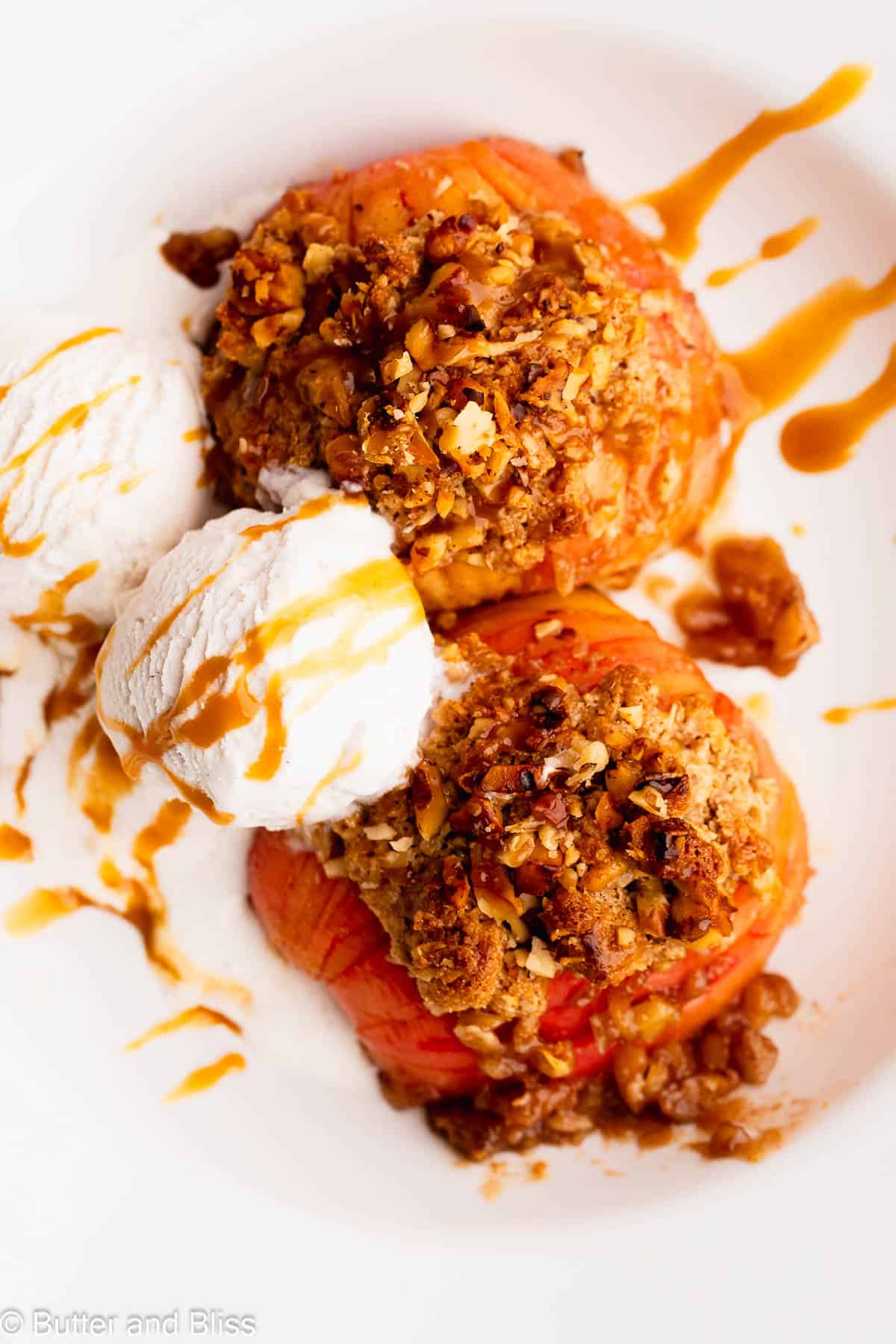 A bowl full of Hasselback apples with buttery streusel and topped with ice cream and caramel.