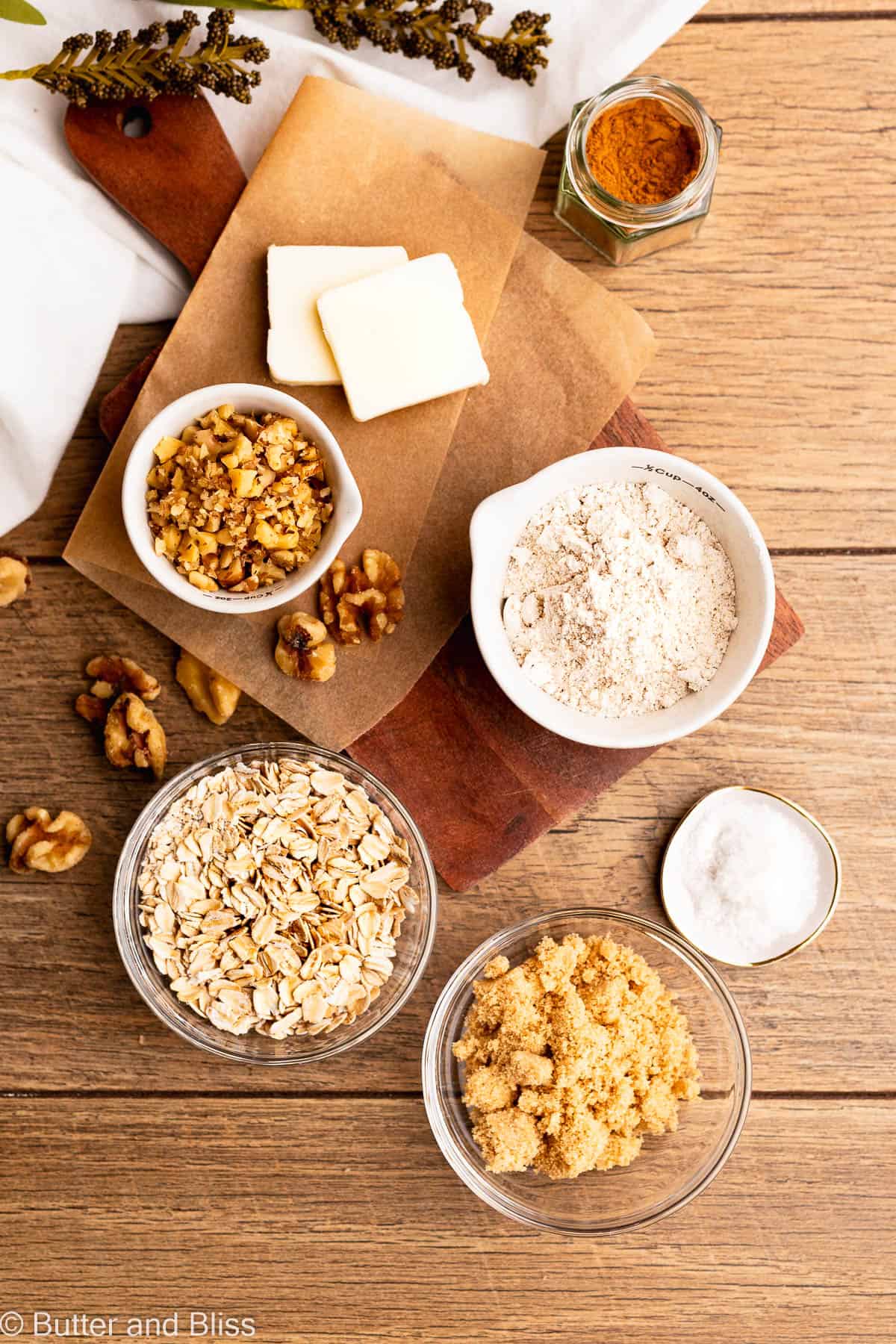 Ingredients for a buttery streusel in small bowls and arranged on a wood table.