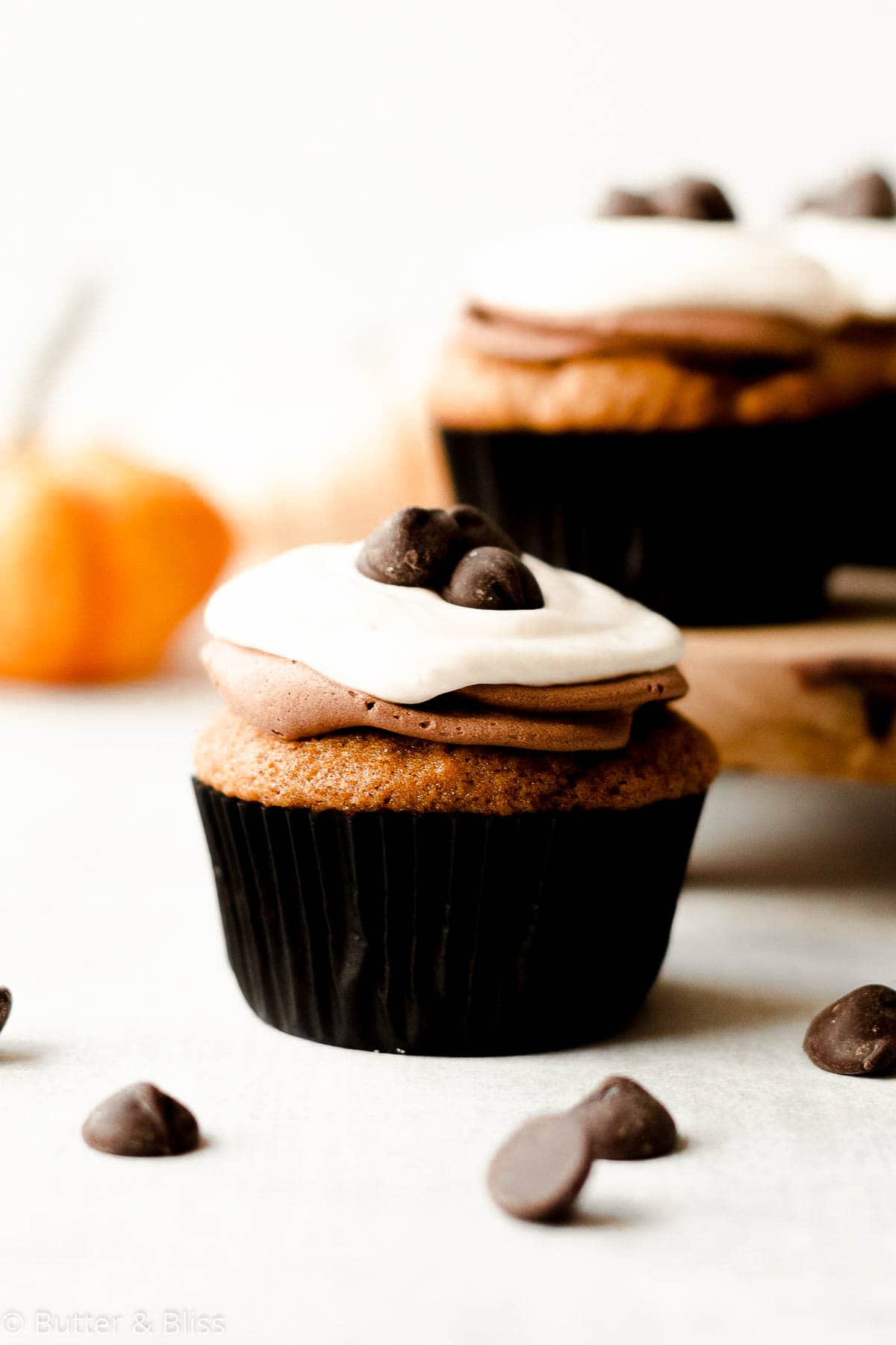 Small batch pumpkin cupcakes on a table with chocolate ganache frosting.