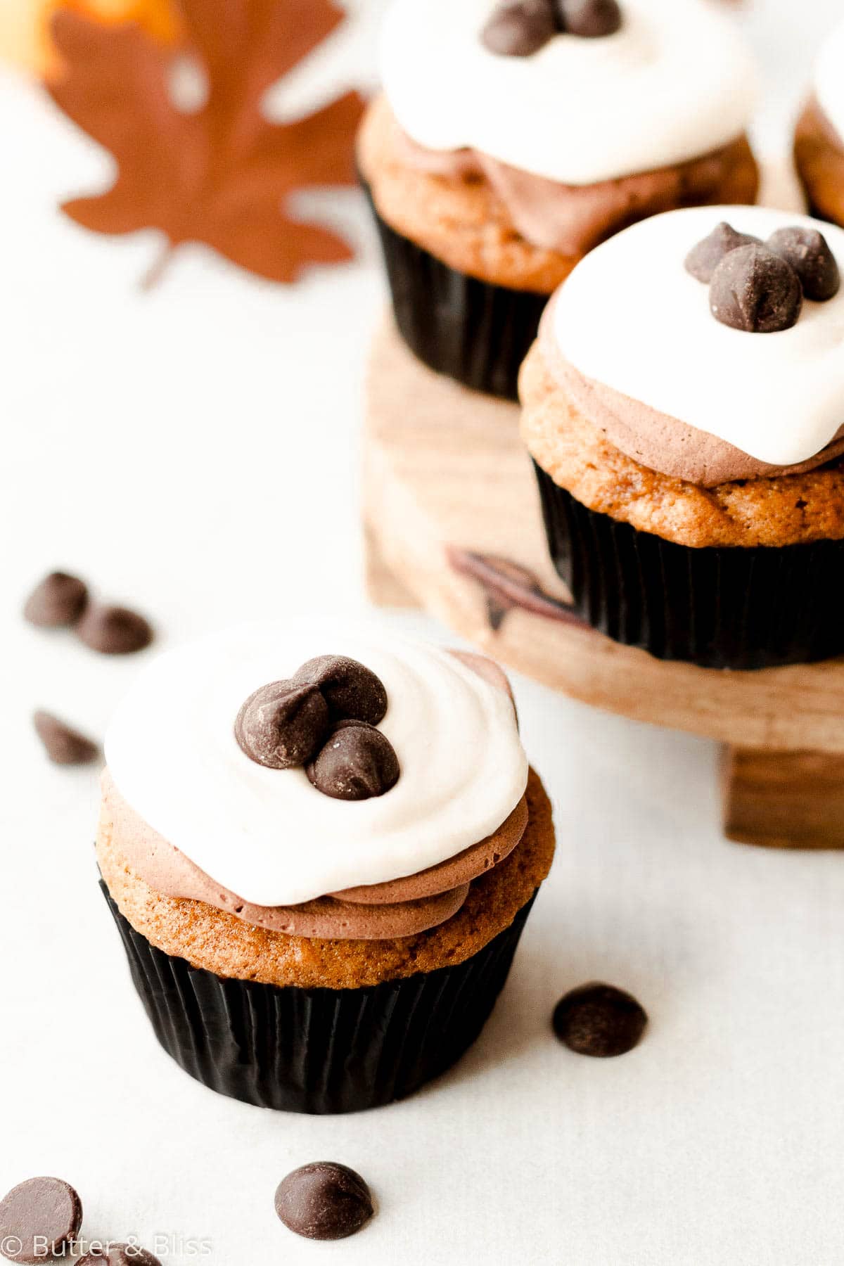 Pretty pumpkin cupcakes with chocolate and cream cheese frosting on a table.