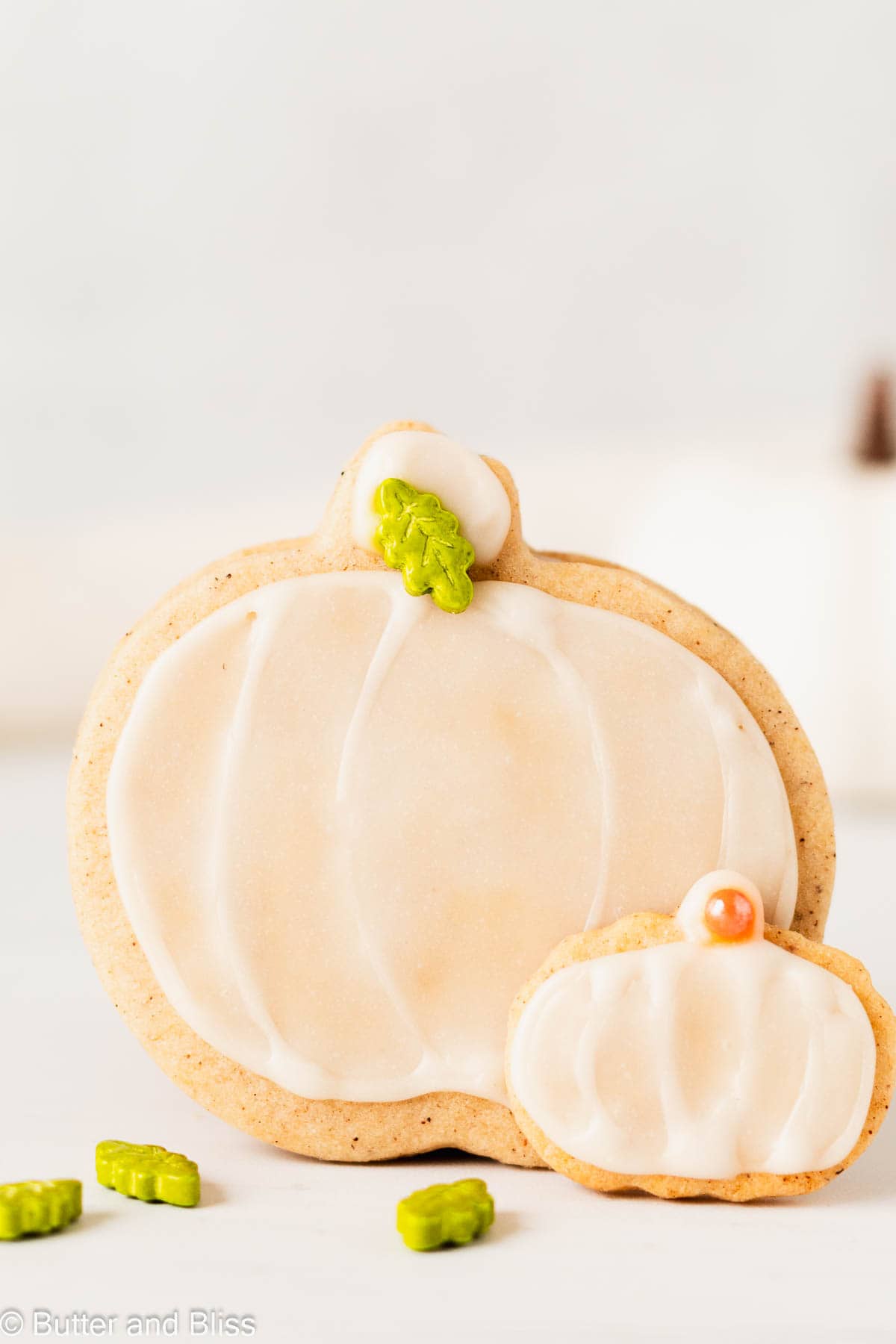 A cute pumpkin spice pumpkin shaped cookie standing up on a table.