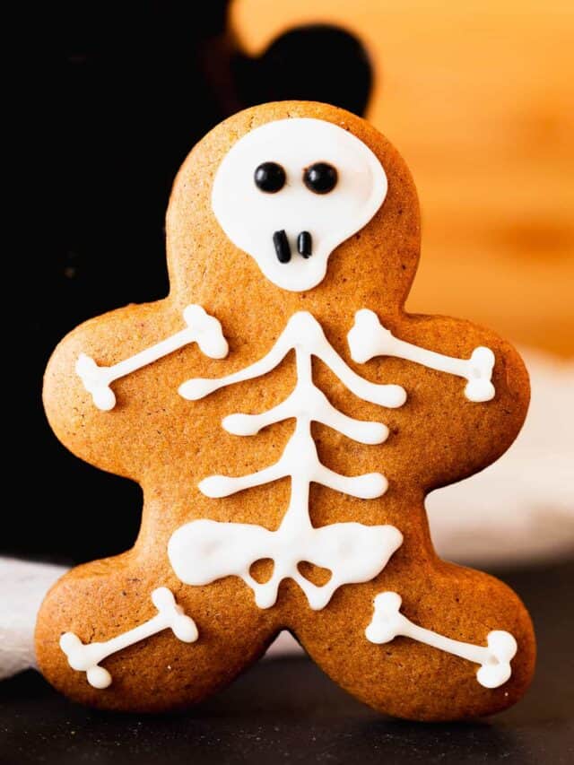 Super cute gingerbread skeleton cut-out cookie propped up on a table.