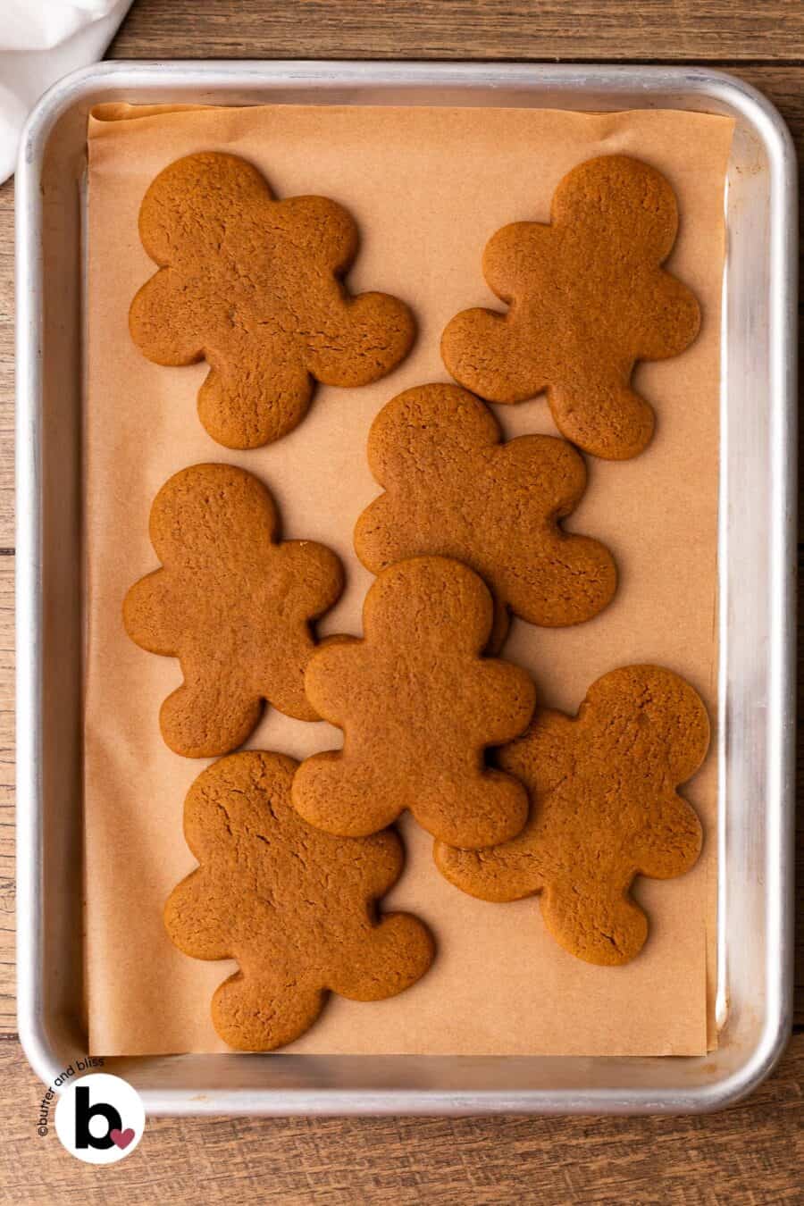 Freshly baked gingerbread men cookies on a parchment lined baking sheet.