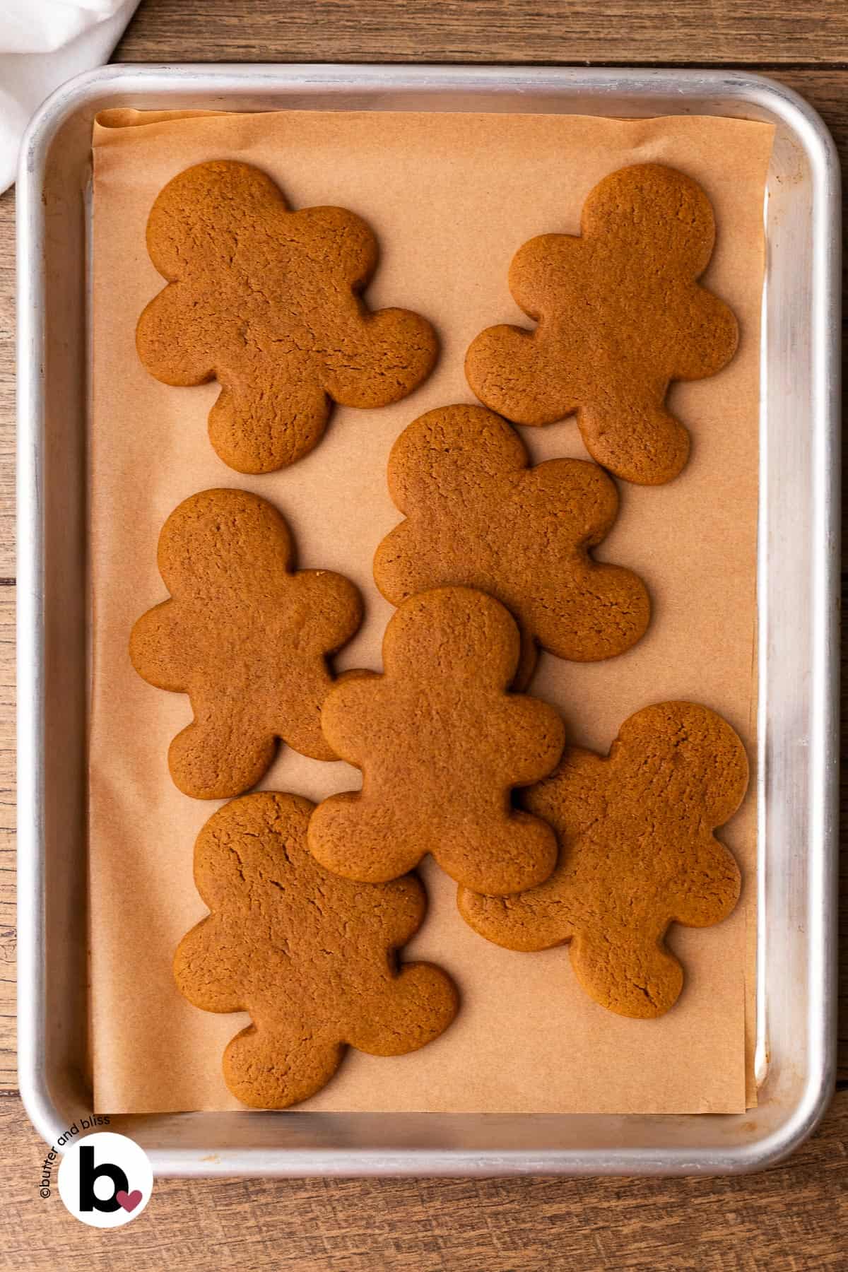 Freshly baked gingerbread men cookies on a parchment lined baking sheet.