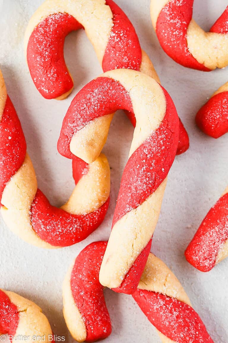 Red and white candy cane cookies in a pile on a table.