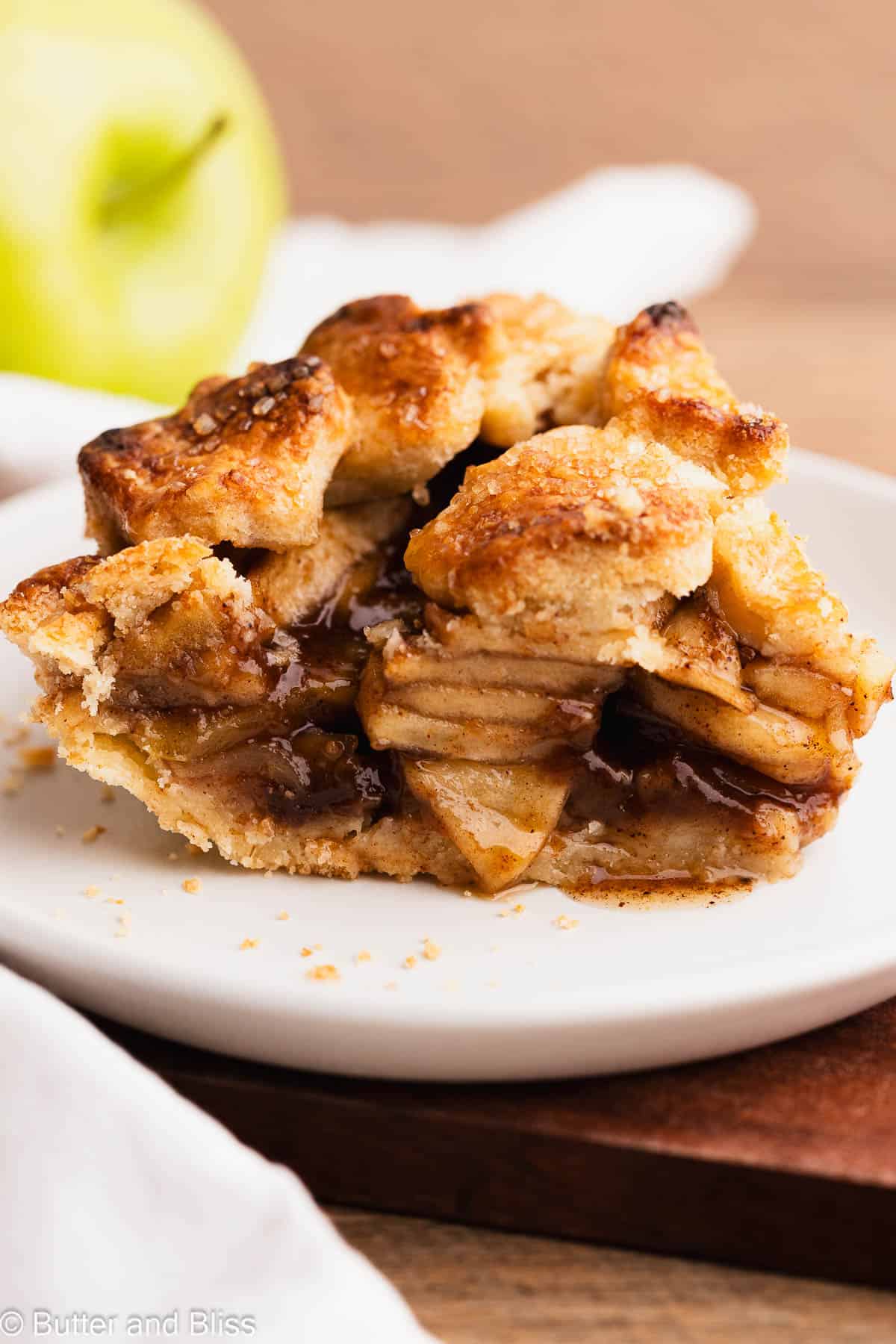 A yummy slice of gluten free apple pie with gooey filling on a white plate.
